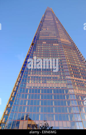 The Shard building in London reflects the pink sunset golden hour glow against a blue sky at dusk Stock Photo