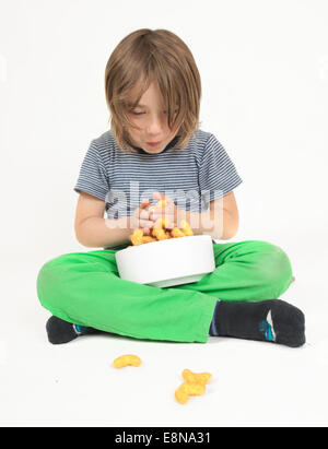 a boy sitting cross legged with bowl full of peanut flips, white background Stock Photo