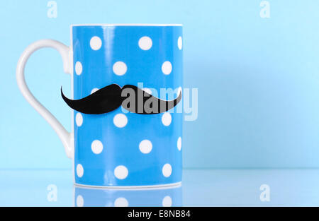 Fundraising for mens health awareness charity with mustache on blue polka dot coffee mug cup on blue background, with copy space Stock Photo