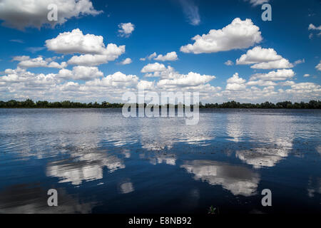 Reflections of white fluffy clouds in a lake on a blue, sky, sunny day Stock Photo