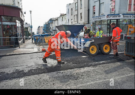 Highway Road workers spread chippings from the Chipper on a resurfaced Main Road Stock Photo