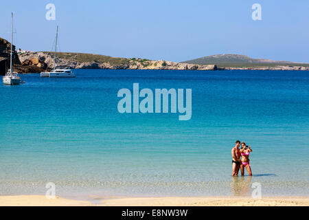 Man and woman on holiday taking a 'selfie' photograph while standing in the sea at Arenal d'en Castell, Menorca, Spain Stock Photo