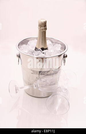 Champagne bottle in cooler and two champagne glasses on bright background Stock Photo