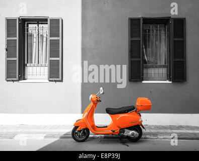 Scooter parked by the curb against orange building in Tel Aviv, Israel Stock Photo