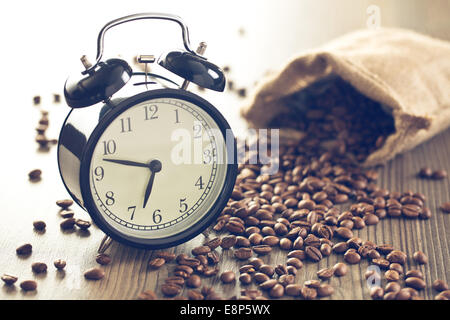 vintage alarm clock and coffee beans on wooden table Stock Photo