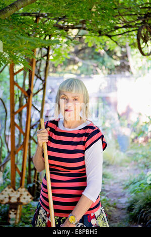 Senior woman in garden with rake Stock Photo