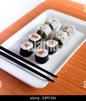 Delicious sushi rolls on white plate with chopsticks Stock Photo