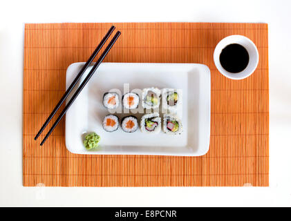 Delicious sushi rolls on white plate with chopsticks Stock Photo