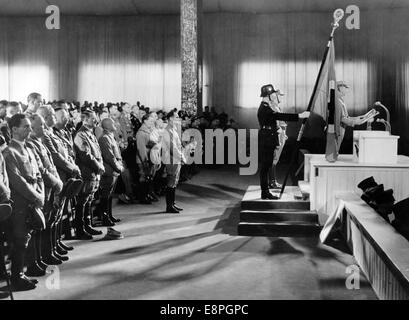 Nuremberg Rally 1936 in Nuremberg, Germany - Opening of the party congress at Luitpold Hall at the Nazi party rally grounds . Chief of staff of the Sturmabteilung (SA) Viktor Lutze reads out the names of the 'martyrs of the Beer Hall Putsch'. Behind him: Standartenfuehrer Jakob Grimminger holding the 'Blood Flag'. First Row L-R: Reich Minister Joseph Goebbels, Head of the German Labour Front Robert Ley, Reich Treasurer Franz Xaver Schwarz, Reichsfuehrer of the Schutzstaffel (SS) Heinrich Himmler, Adolf Hitler, Gauleiter Julius Streicher, Hermann Goering, Reich Minister Bernhard Rust. In fro Stock Photo