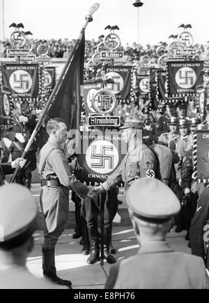 Nuremberg Rally 1936 in Nuremberg, Germany - Adolf Hitler consecrates the new standards with the 'Blood Flag' during the roll call of the Sturmtruppe (SA), Schutzstaffel (SS) and National Socialist Motor Corps (NSKK). New standards of SA and SS were 'consecrated' by touching them to the 'Blood Flag', which supposedly was carried in the failed Beer Hall Putsch. (Flaws in quality due to the historic picture copy) Fotoarchiv für Zeitgeschichtee - NO WIRE SERVICE - Stock Photo