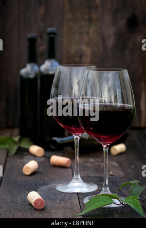 Glass of red wine with corks on old wooden table Stock Photo