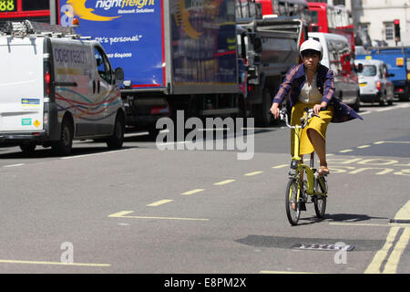 A female cyclist riding alone along a London road - traffic queuing on the other side Stock Photo