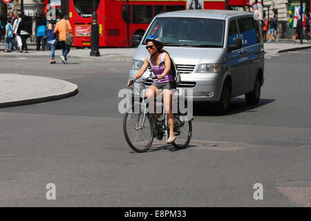 A female cyclist riding in front of a van in London Stock Photo
