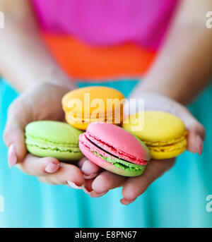 Girl holding colorful French macaroons in hands Stock Photo