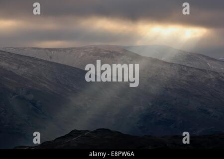 A shaft of sunlight bursts through clouds with the Helvellyn mountain range as backdrop in the Lake District, Cumbria, UK. Stock Photo