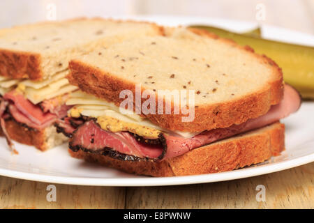 Pastrami sandwich on Jewish Rye bread with swiss cheese, mustard, and kosher dill pickles Stock Photo