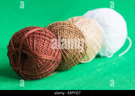 A row from balls of a multi-colored yarn on a green background Stock Photo