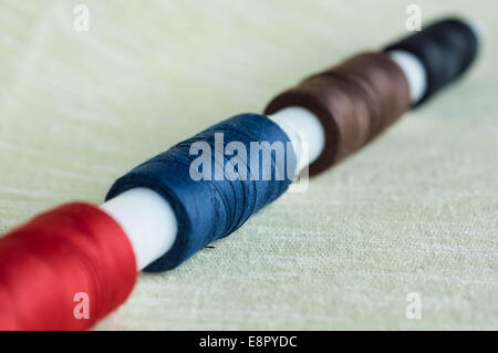 A row from coils of threads on a textile background Stock Photo