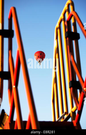 Lady bird balloon flies over a children,s play ground. viewed between a slides railings. Stock Photo