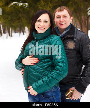 Happy young pregnant couple having fun in the winter park Stock Photo