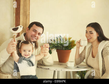 Happy smiling family with one year old baby girl drinking coffee indoor Stock Photo