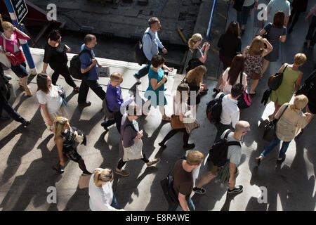 Passengers getting off trains and walking towards ticket gates at Brighton Train Station during a busy summer morning. Stock Photo