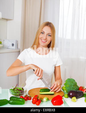 Young smiling woman cutting vegetables at the kitchen Stock Photo