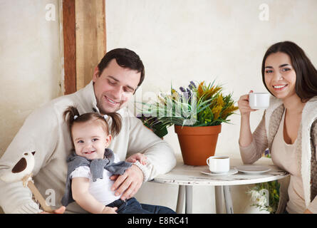 Happy smiling family with one year old baby girl drinking coffee indoor Stock Photo