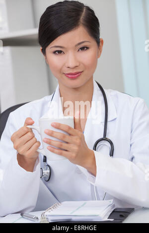 Reassuring Chinese Asian female medical doctor drinking tea or coffee in a hospital office Stock Photo