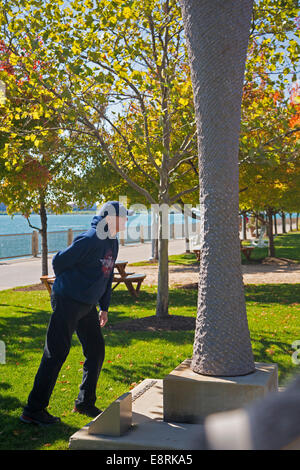 Detroit, Michigan - A visitor studies sculpture on the Detroit Riverwalk. Stock Photo