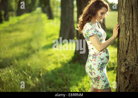 Attractive young mother walking among the old trees Stock Photo