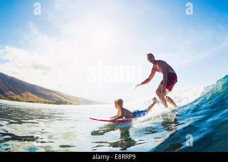 Father and Son Surfing Together Riding Blue Ocean Wave Stock Photo
