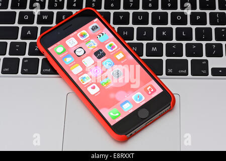 iPhone 6 in red case on an Apple Macbook keyboard Stock Photo