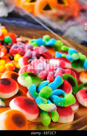 a pile of different Halloween candies with scary ornaments in the background, such as pumpkins and cobwebs Stock Photo