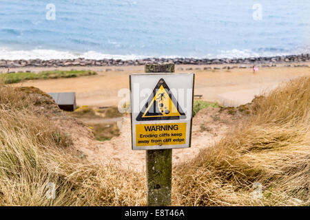 Caution falling cliffs sign on the cliff edge at Highcliffe overlooking the sea Stock Photo