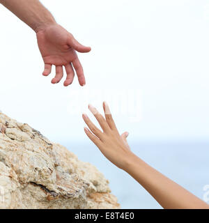 Man and woman hands helping concept with the sea in the background Stock Photo