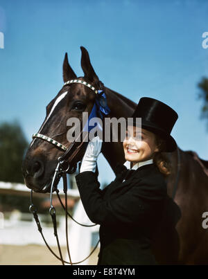 1940s 1950s SMILING TEEN GIRL WEARING TOP HAT TUXEDO WHITE GLOVES POSING WITH HORSE BLUE RIBBON WINNER FIRST PLACE Stock Photo