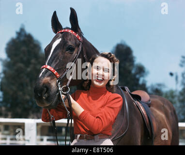 1940s 1950s SMILING TEEN GIRL POSING STANDING WITH HORSE Stock Photo