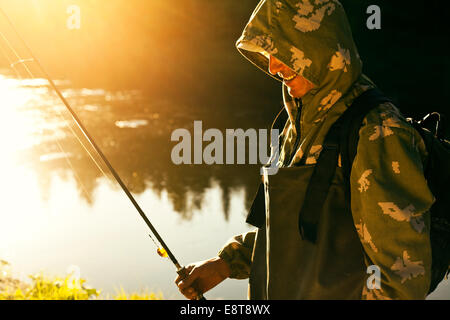 Mari man holding fishing rod at lake Stock Photo