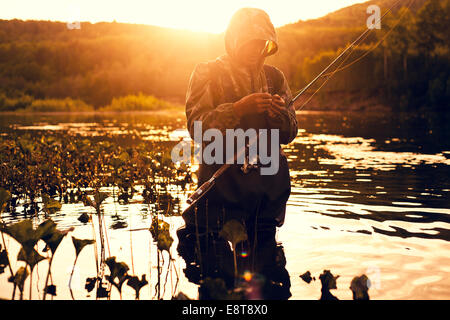 Mari fisherman preparing hook in lake Stock Photo