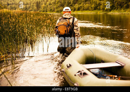 Mari fisherman pulling boat through lake Stock Photo