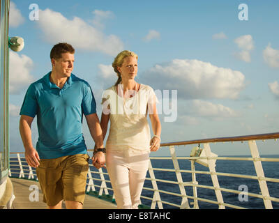 Caucasian couple holding hands on boat deck Stock Photo