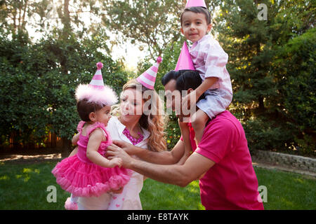 Family wearing party hats together in backyard Stock Photo