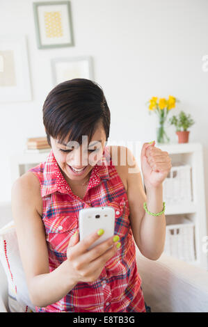 Happy mixed race woman cheering with cell phone Stock Photo