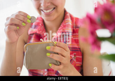 Mixed race woman putting coin into purse Stock Photo