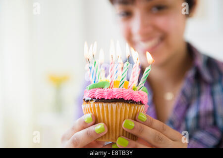 Mixed race woman holding cupcake with birthday candles Stock Photo