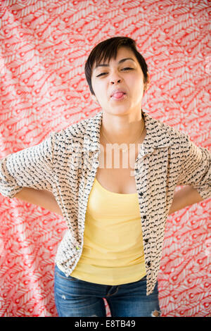 Mixed race woman sticking out tongue Stock Photo