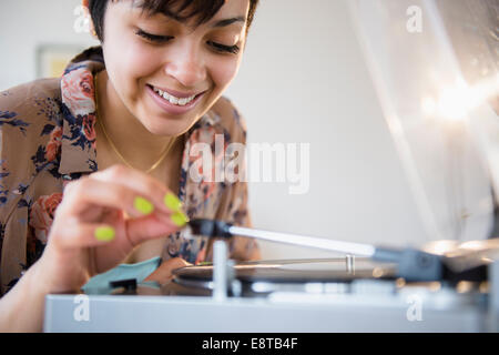 Smiling mixed race woman playing vinyl record Stock Photo