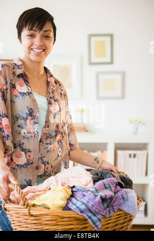 Mixed race woman holding basket of dirty laundry Stock Photo