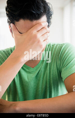 Frustrated mixed race man covering his face Stock Photo